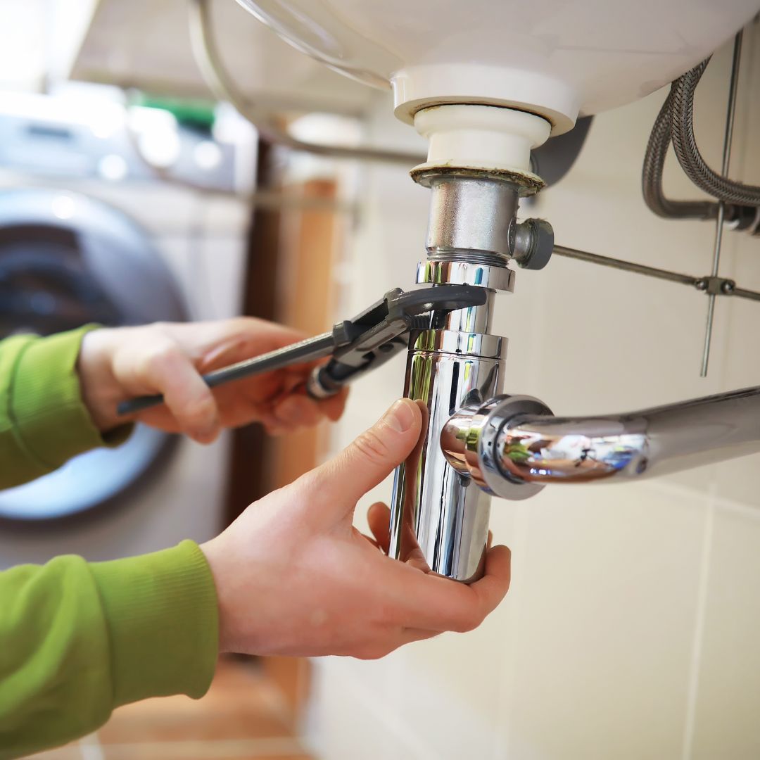 Professional plumber fixing bathroom pipeline with tools